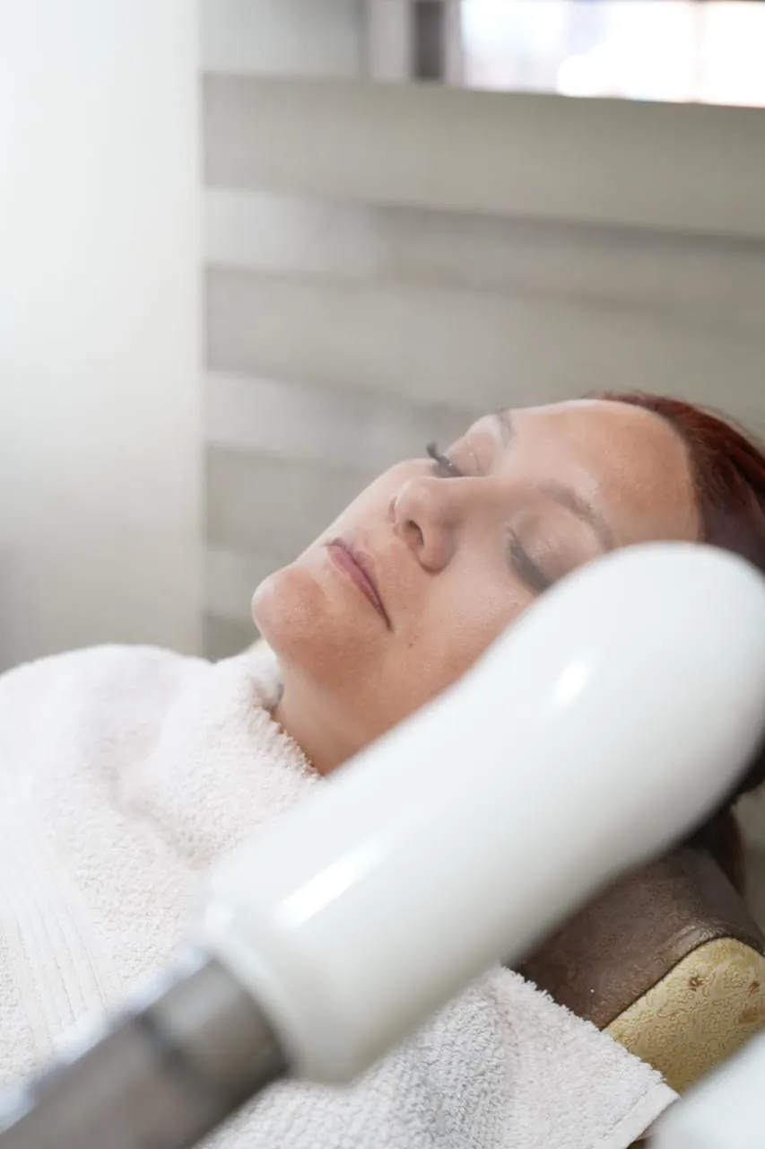 Clienta relajada con vapor durante un tratamiento facial